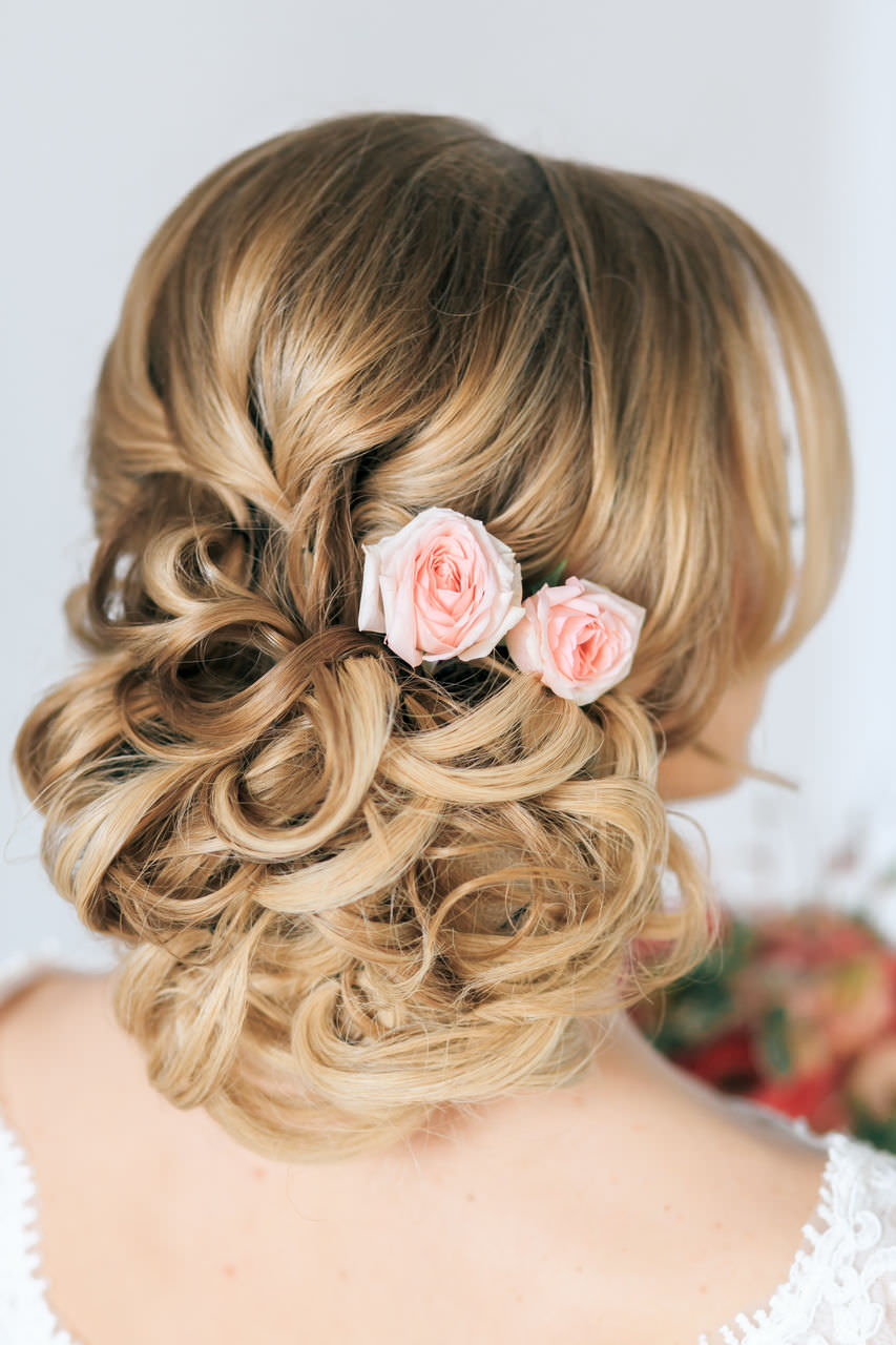 На фото: весільна зачіска з локонами і прикрасами у вигляді квітів.