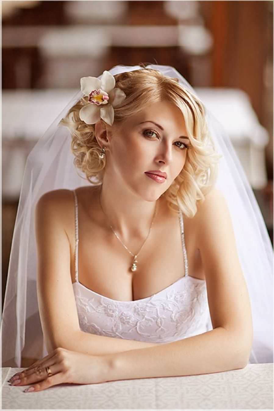 На фото: весільна коротка зачіска  з фатою і з квіткою збоку у волоссі.